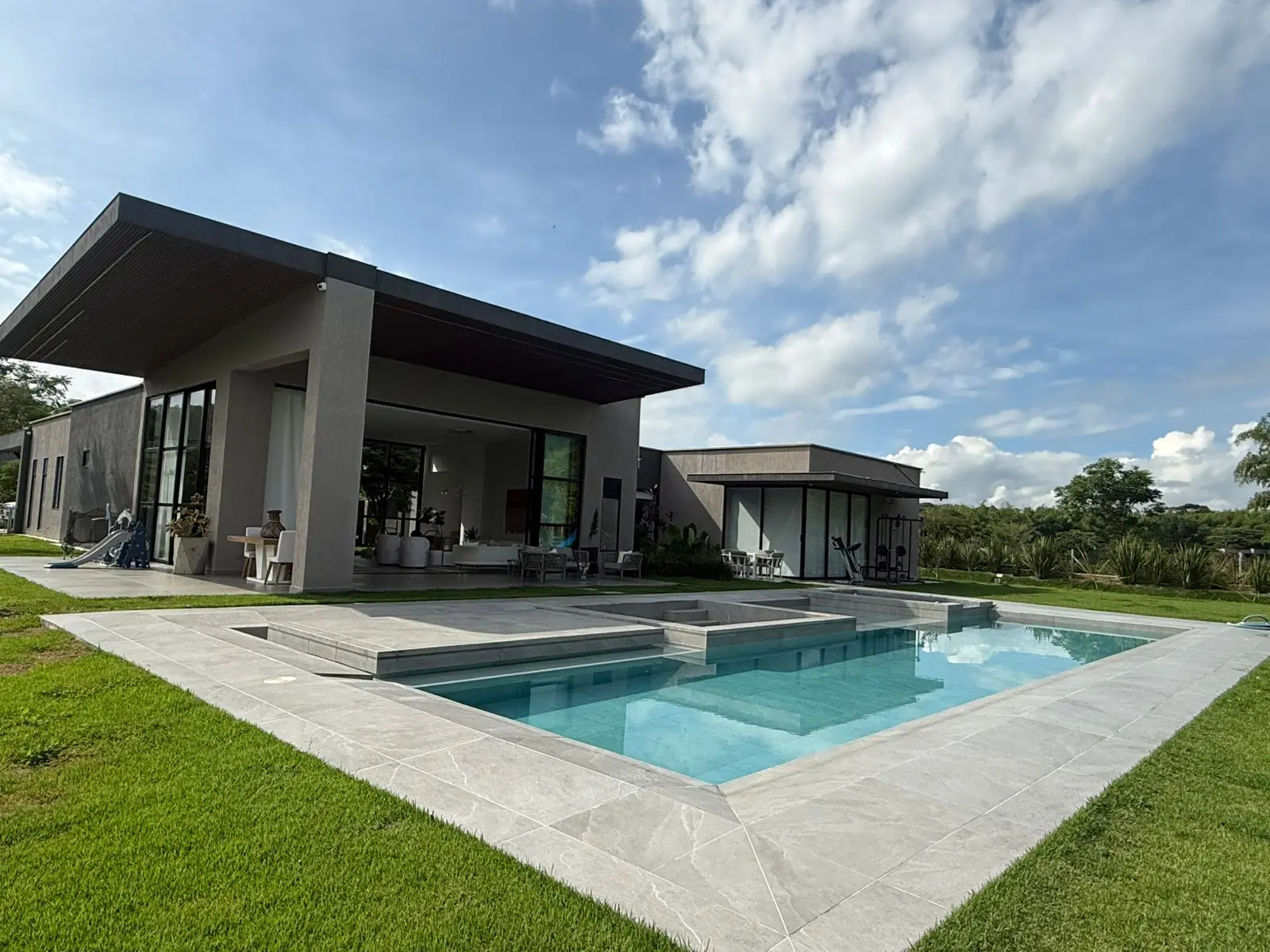 Fachada posterior de Casa Acacia con piscina, losa en voladizo y ventanería de piso a techo