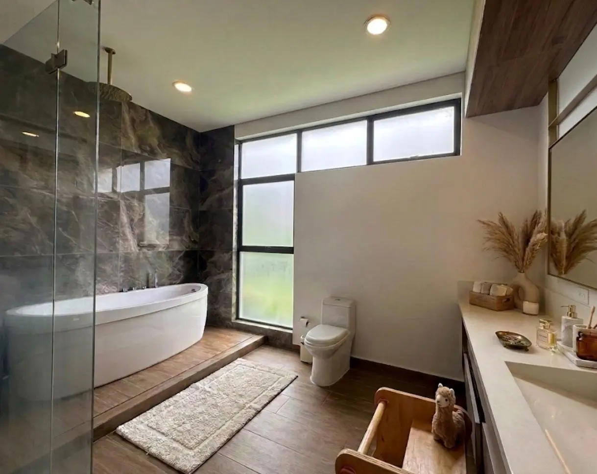 Baño principal con bañera exenta y muro de piedra